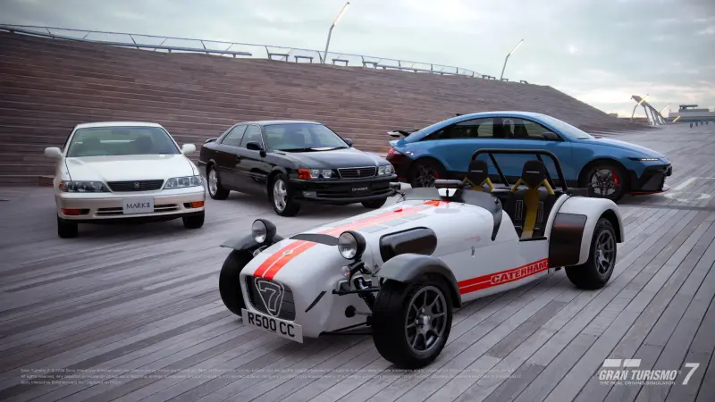 The four cars added in Gran Turismo 7 update 1.71 parked on a boardwalk: a white Toyota Mark II, a black Toyota Chaser, a blue Hyundai IONIQ 6 N and a white Caterham Seven Superlight R500