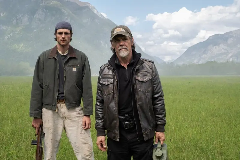 Jacob Elordi and Josh Brolin stand together in a green mountain valley in The Dog Stars